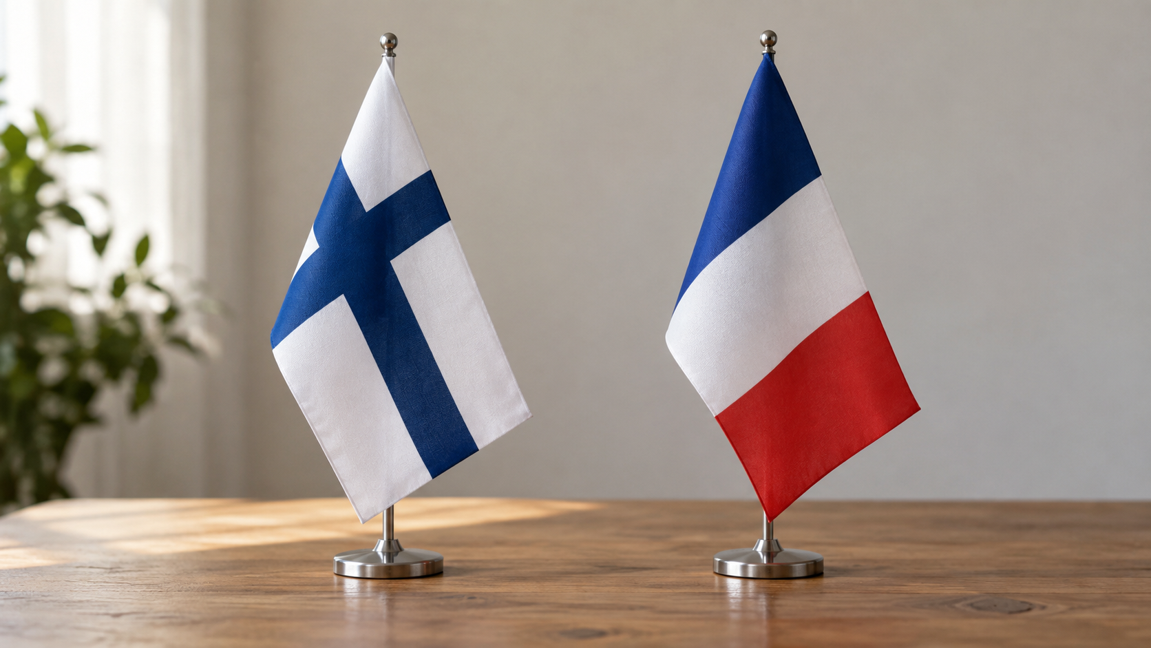 Finnish and French cloth flags on a wooden table, illustrating forward deterrence cooperation.